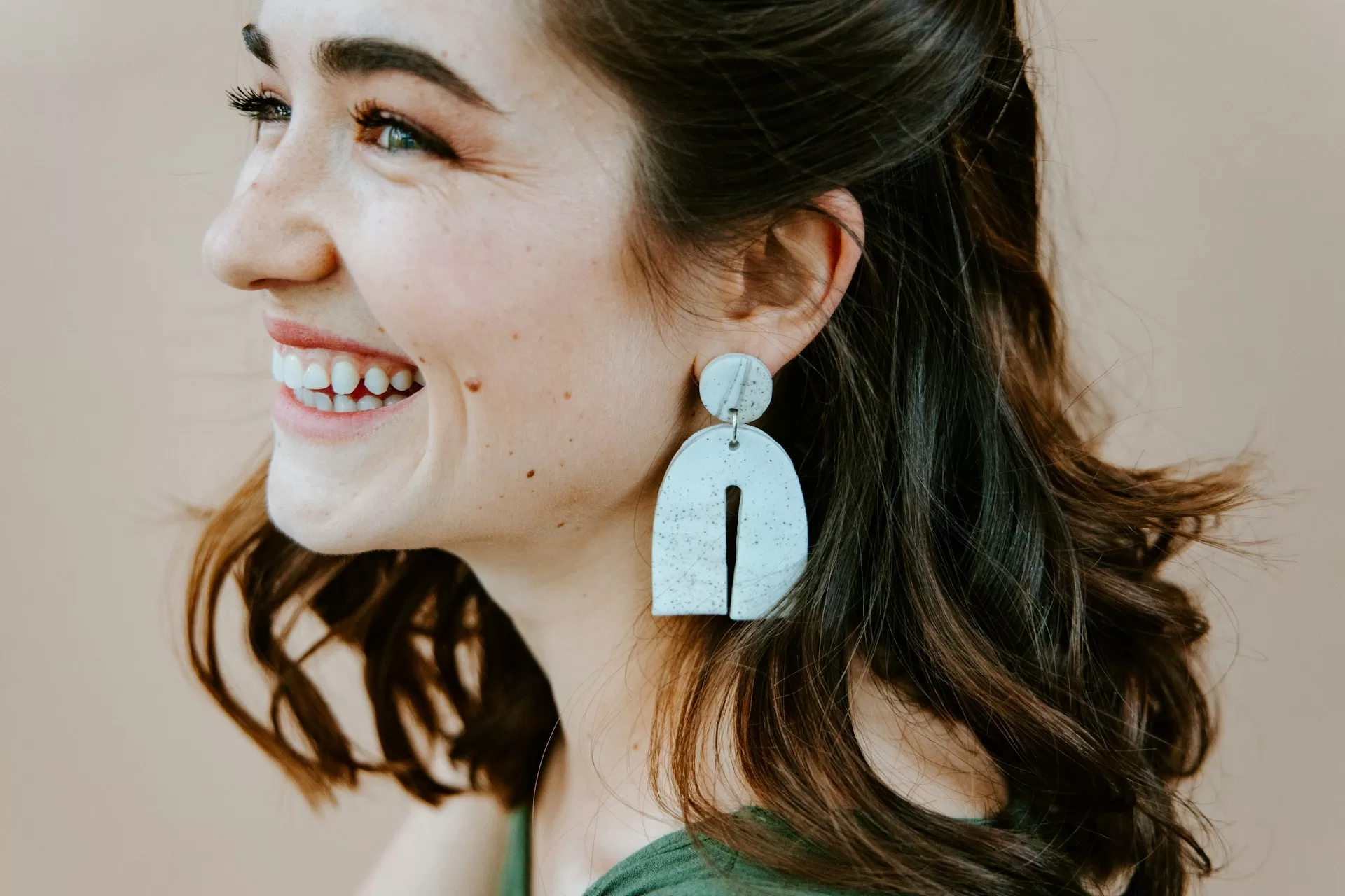uśmiechająca się kobieta z ceramicznym kolczykiem w uchu