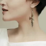 Duży kolczyk w kształcie ptaka w uchu kobiety o krótkich włosach